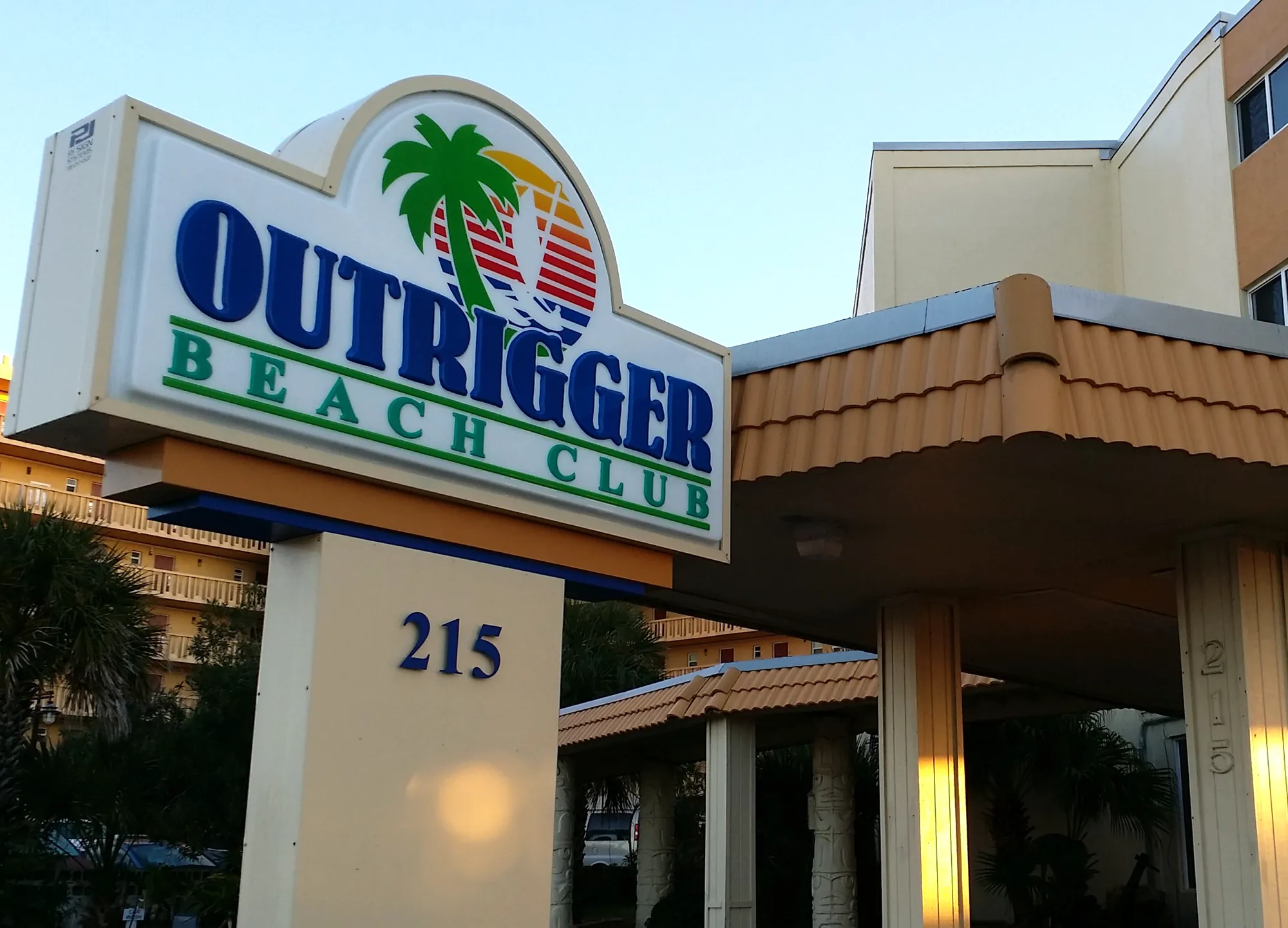 Outrigger Beach Club entrance sign with palm tree logo and covered driveway.