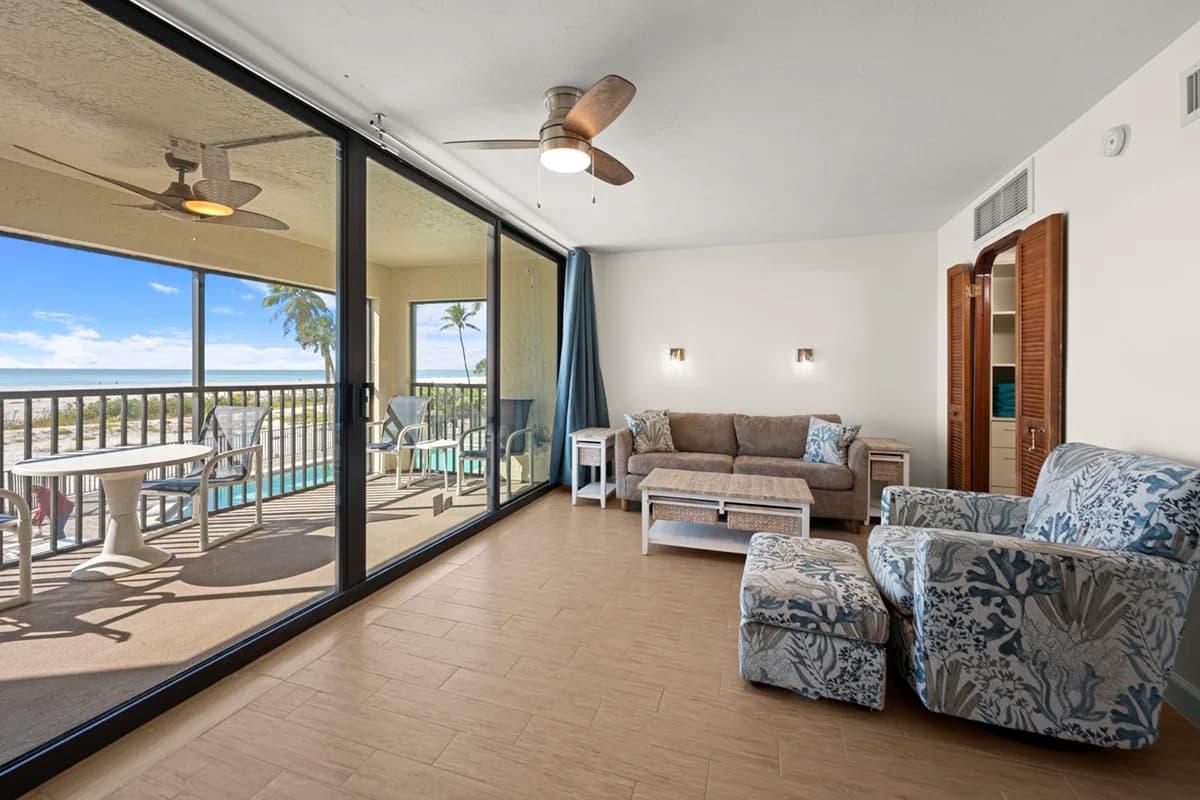 Spacious living room with seating area and sliding glass doors opening to a beachfront balcony
