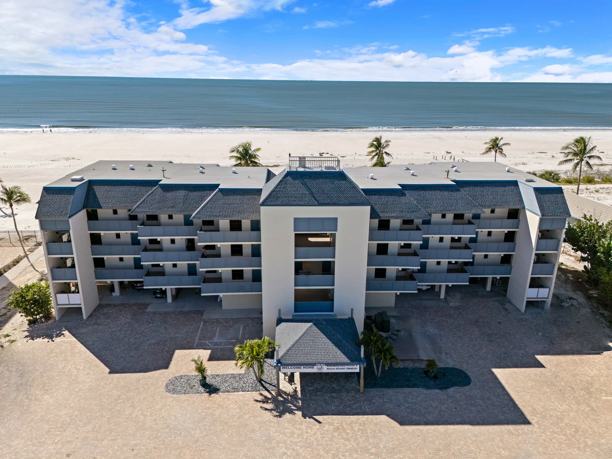 Aerial view of the beachfront Mariners Boathouse resort with the ocean and sandy shoreline behind it